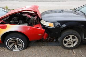 A person standing next to two damaged cars exchanging information and taking photos with a smartphone.